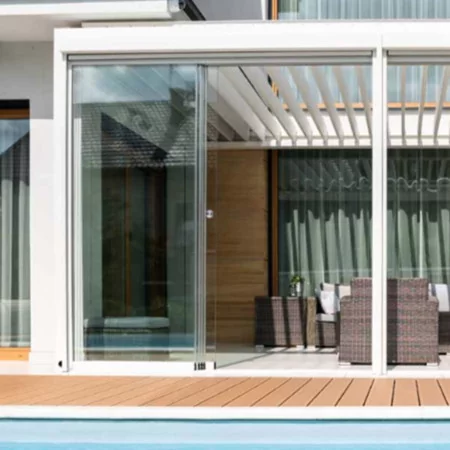 Pergola bioclimatique DETENTE à adossée lames perpendiculaires avec vitrages coulissants