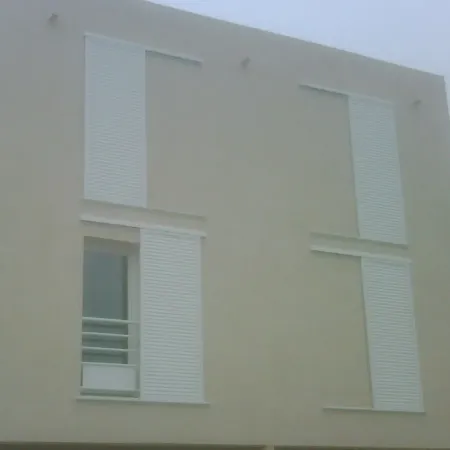 Façade d’immeuble moderne avec volets coulissants blancs en aluminium, installation extérieure sur fenêtres