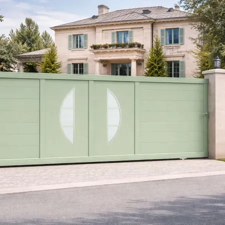 Portail coulissant en aluminium RAL 6021 intégré dans une grande clôture, vu de côté, devant une grande maison de standing