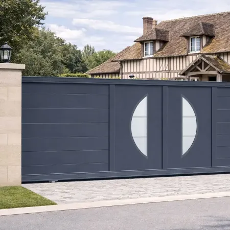 Portail coulissant en aluminium RAL 7016 intégré dans une grande clôture devant une grande maison normande à colombages