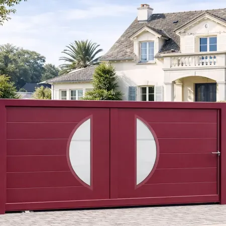 Portail coulissant en aluminium RAL 3005 installé entre deux piliers en pierre, intégré dans une clôture