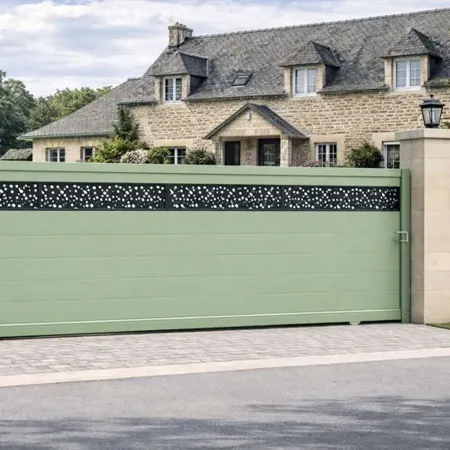 Portail coulissant en aluminium RAL 6021 intégré dans une clôture avec piliers en pierre devant une grande maison bretonne