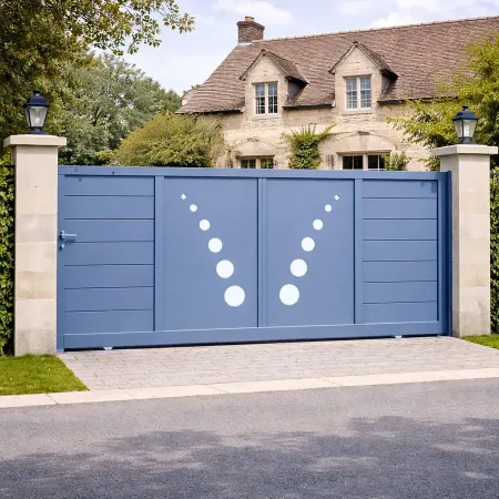 Portail coulissant en aluminium RAL 5014 installé dans une clôture, en vue de côté, devant une maison ancienne en pierre