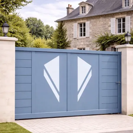 Portail coulissant en aluminium RAL 5014 vu de côté, intégré dans une clôture avec piliers en pierre devant une maison ancienne