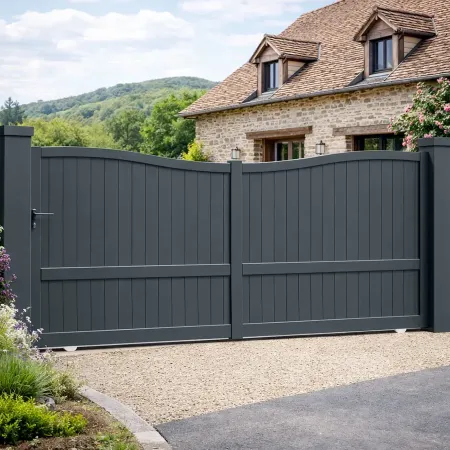 Portail coulissant en aluminium RAL 7016 installé devant une maison contemporaine avec jardin paysager et allée gravillonnée.