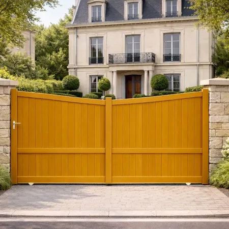 Portail coulissant en aluminium RAL chêne doré avec piliers en pierre, installé devant une maison classique.