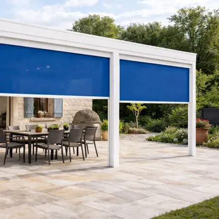 Pergola blanche RAL 9010 avec store vertical ZIP bleu sur terrasse en pierre d’une maison style provençal
