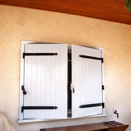 Volet battant aluminium et précadre en RAL 9010 blanc pur sur façade rénovée de maison individuelle, style méditerranéen.