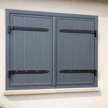 Volet battant aluminium gris anthracite avec pentures noires installé sur façade en enduit clair, style maison contemporaine.