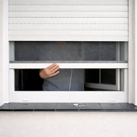 Volet roulant électrique blanc avec moustiquaire intégrée partiellement ouverte, vue intérieure sans reflet