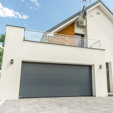 Porte de garage sectionnelle anthracite sur maison contemporaine avec balcon et façade moderne en enduit clair et bois