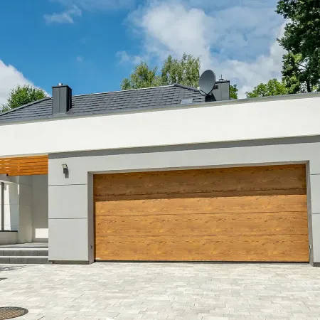 Porte de garage sectionnelle imitation bois sur maison moderne avec allée pavée et extérieur contemporain paysager