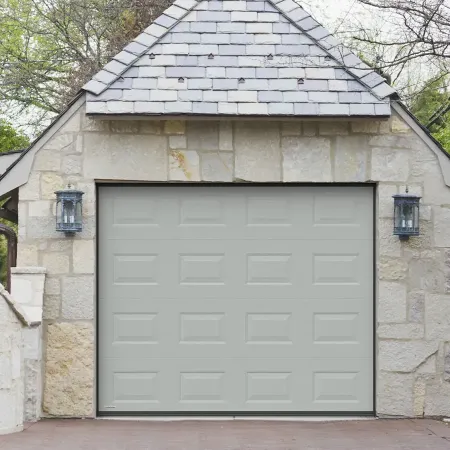 Porte de garage sectionnelle grise installée sur maison en pierre avec façade traditionnelle et architecture classique