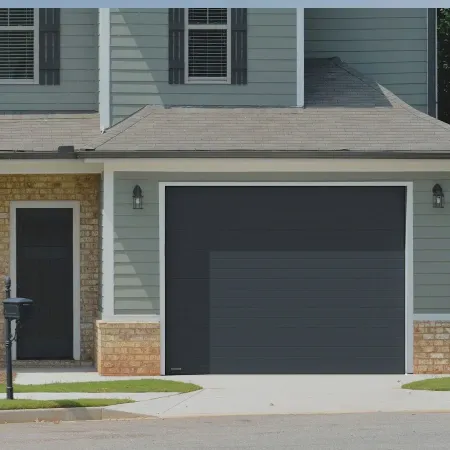 Porte de garage sectionnelle noire installée sur maison style américain avec façade en brique et bardage extérieur