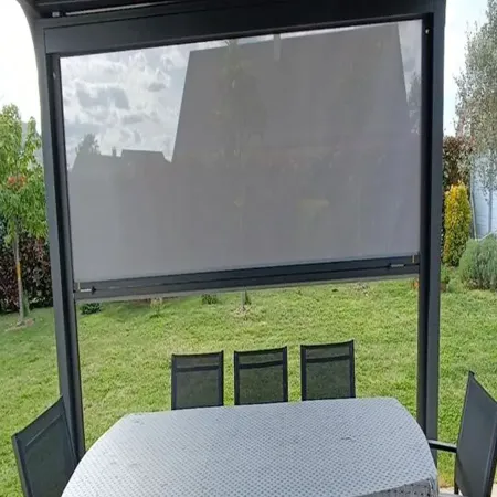 Vue intérieure pergola avec store ZIP anthracite et toile grise au-dessus d’un salon de jardin sur terrasse