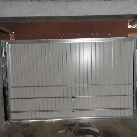 Mécanisme intérieur d’une porte de garage basculante avec rails métalliques et ressorts latéraux dans un box en sous-sol