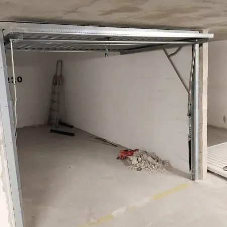 Installation en cours d’une porte de garage basculante dans un box en sous-sol avec rails métalliques et outils de chantier