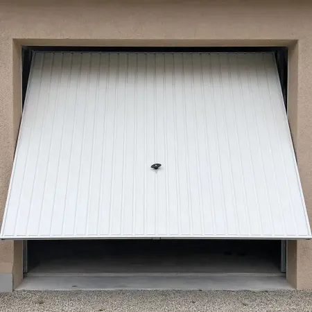 Porte de garage basculante blanche vue de l’extérieur d’une maison, partiellement ouverte