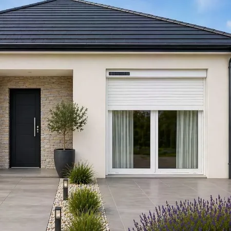 Volet roulant solaire RAL 9010 sur porte-fenêtre de maison moderne avec terrasse carrelée et façade extérieure