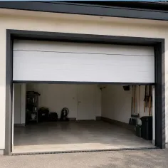 Porte de garage sectionnelle motorisée installée à l’intérieur d’un garage avec rails au plafond et ouverture partielle 2
