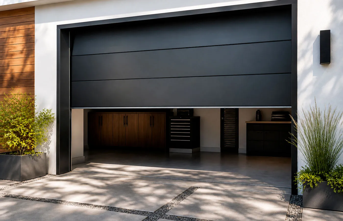 Porte de garage sectionnelle motoris&eacute;e en aluminium noir anthracite, partiellement ouverte, avec excellente isolation thermique et design moderne.