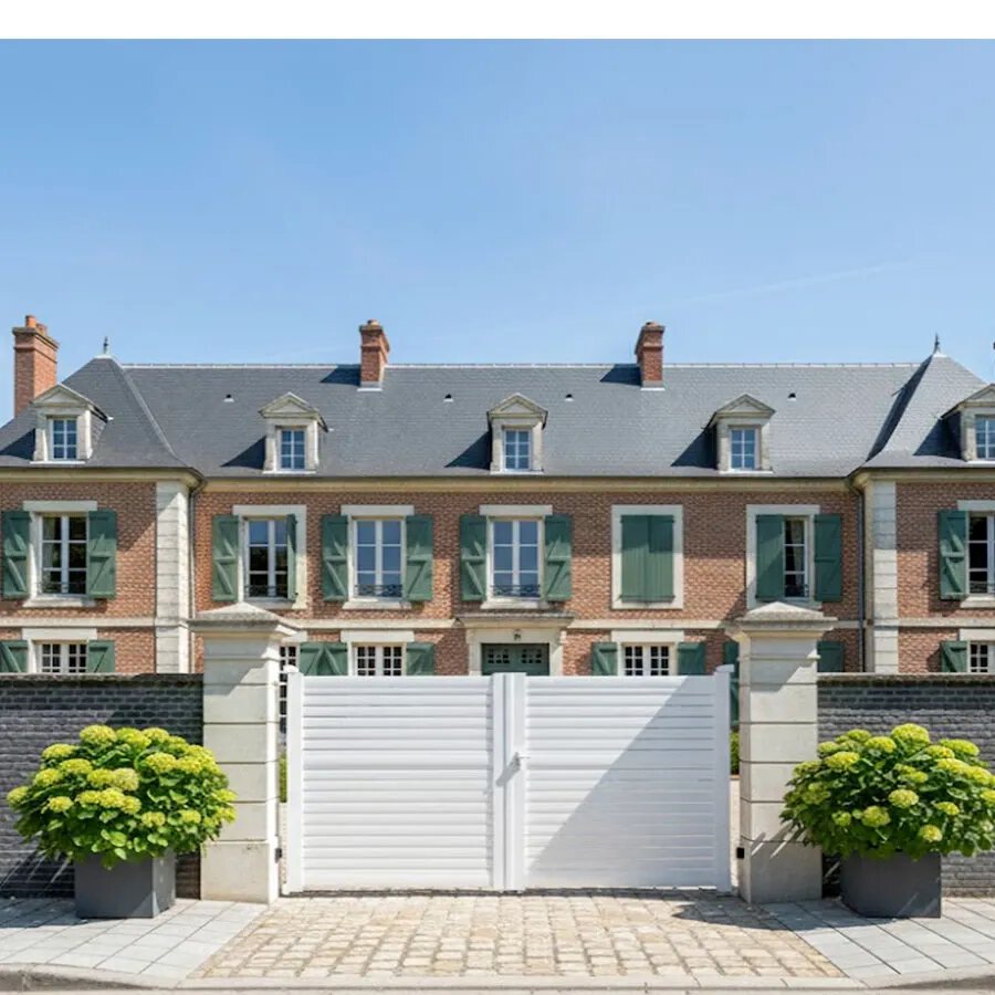 Portail aluminium BAGO blanc entre deux piliers, devant une demeure classique