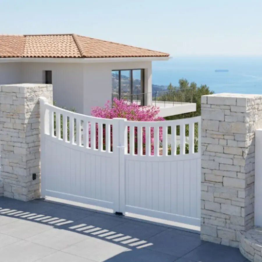 Portail aluminium BEN blanc entre deux piliers, devant une maison de bord de mer