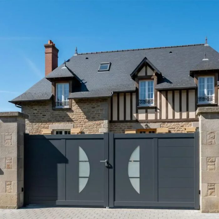 Portail aluminium BYL gris anthracite devant une maison à colombages