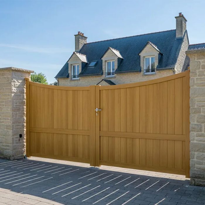 Portail aluminium GALAPE chêne doré devant une maison à toit d'ardoise