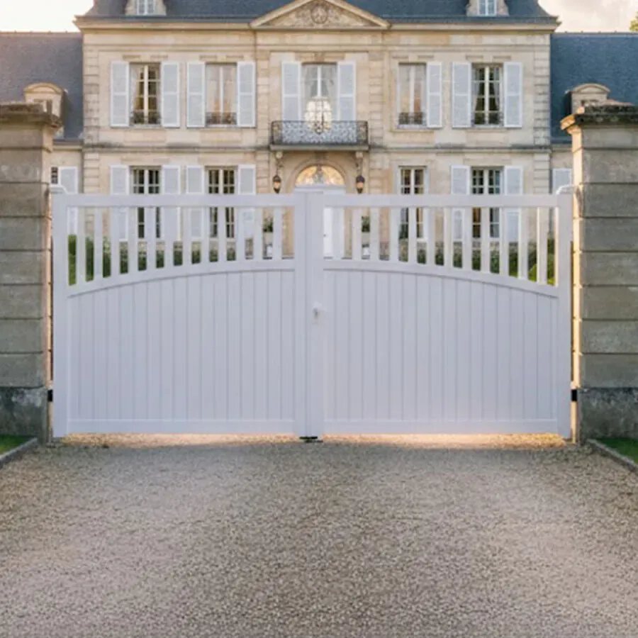 Portail aluminium KIMI blanc entre deux piliers, devant une demeure de caractère