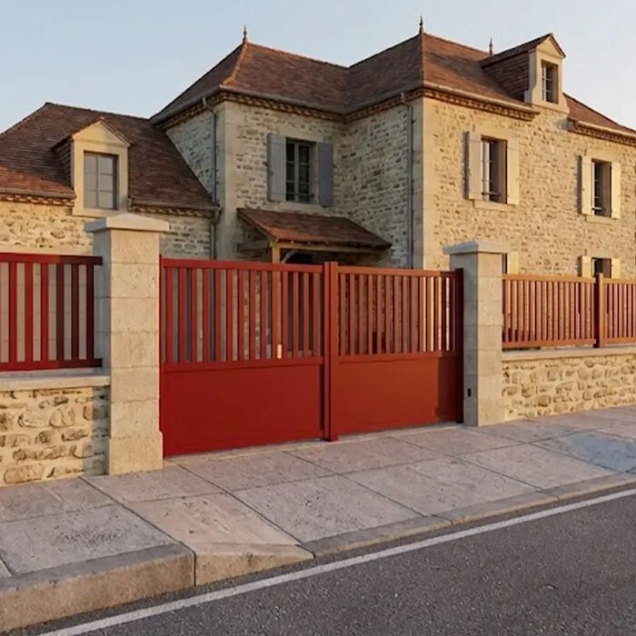 Portail aluminium KIN rouge devant une maison en pierre