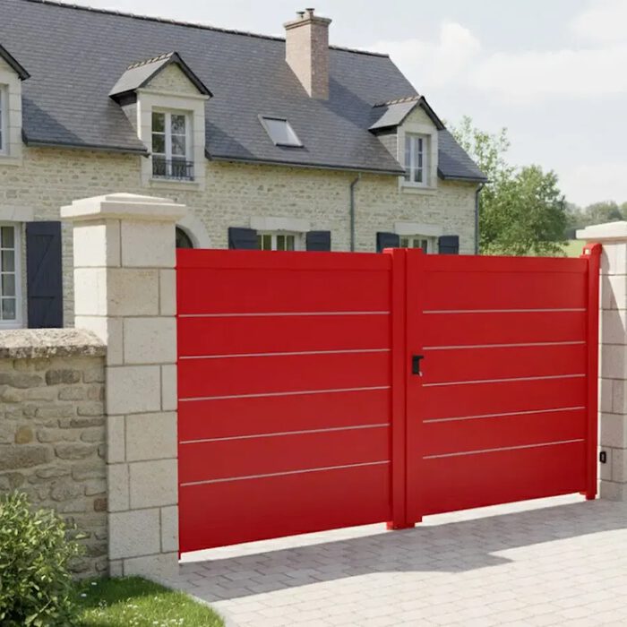 Portail aluminium TAY rouge devant une maison en pierre