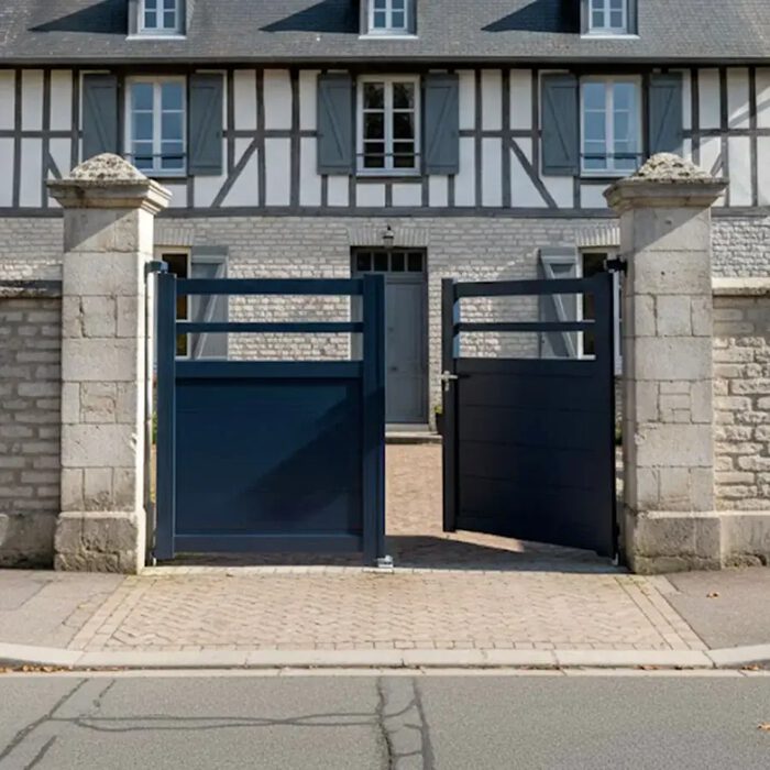 Portail aluminium TROM bleu nuit devant une maison à colombages