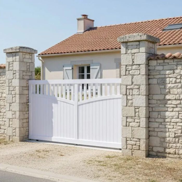 Portail coulissant GO blanc devant une maison en pierre