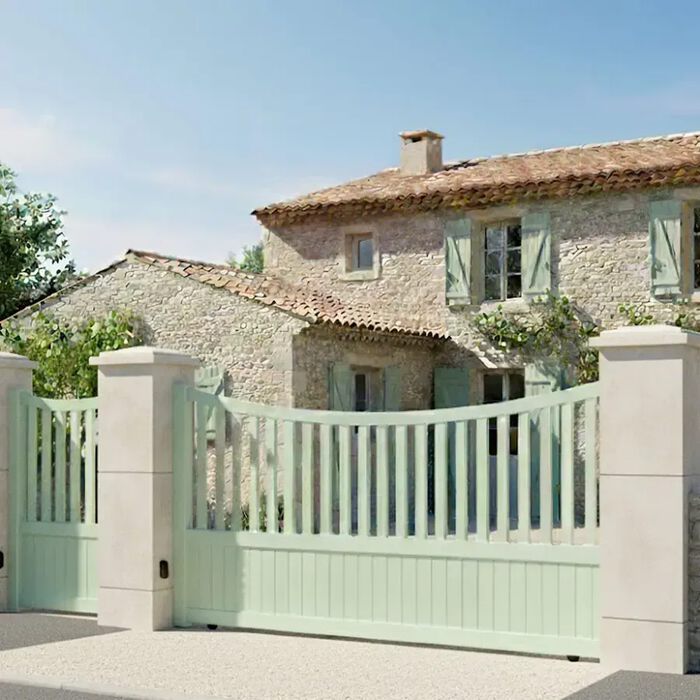Portail coulissant ICO vert pâle devant une maison en pierre