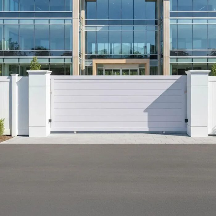 Portail coulissant TIC blanc devant un immeuble de bureaux