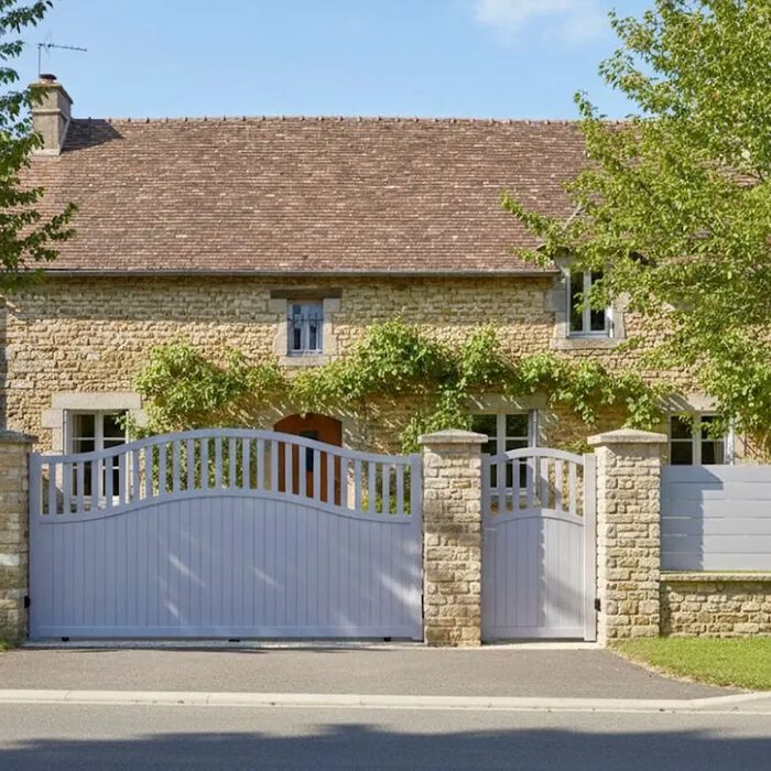 Portail coulissant TOC blanc et portillon assorti devant une maison en pierre
