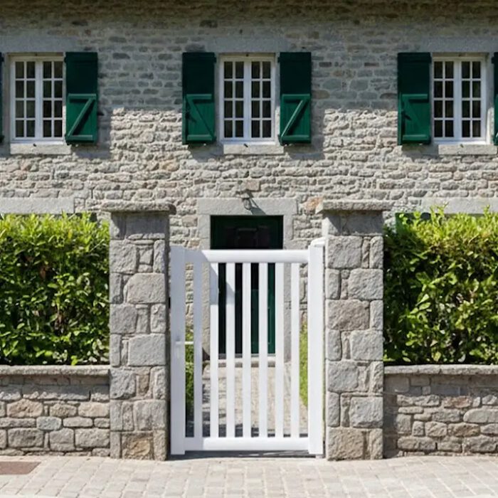 Portillon aluminium DEN blanc devant une maison à volets verts