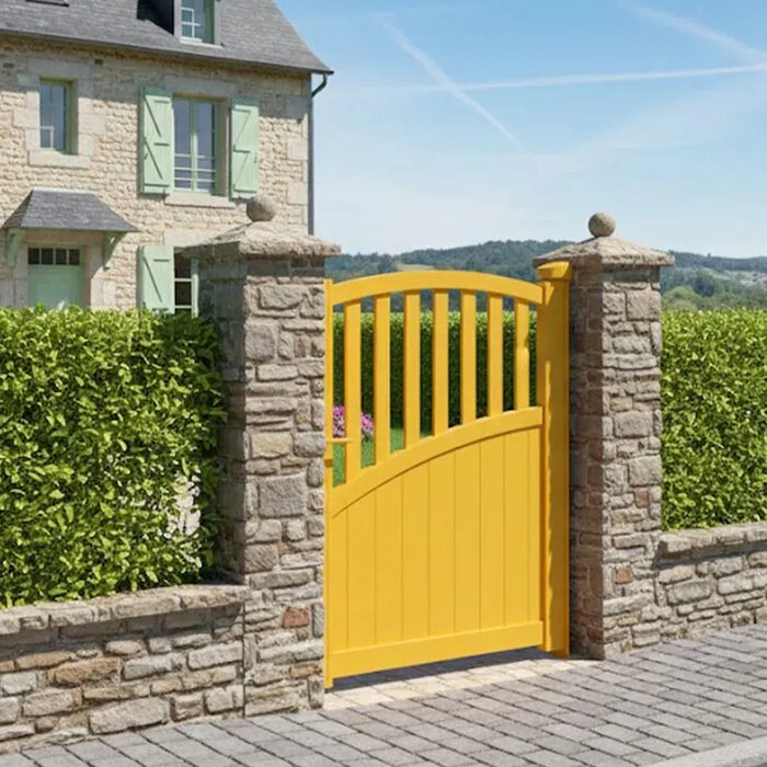 Portillon aluminium LANZA jaune entre deux piliers en pierre