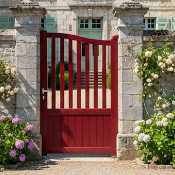 Portillon aluminium LEV rouge devant une maison fleurie