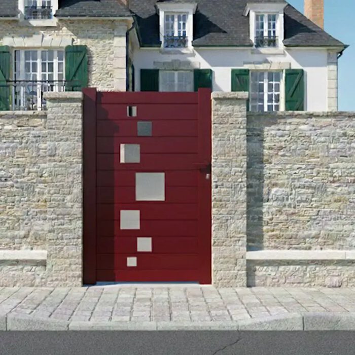 Portillon aluminium SOM rouge devant une maison en pierre