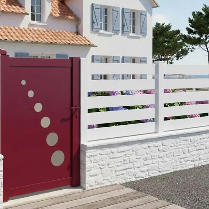 Portillon aluminium TRAI rouge devant une maison de bord de mer