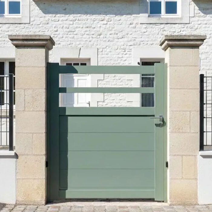 Portillon aluminium TROM vert pâle devant une maison en pierre blanche
