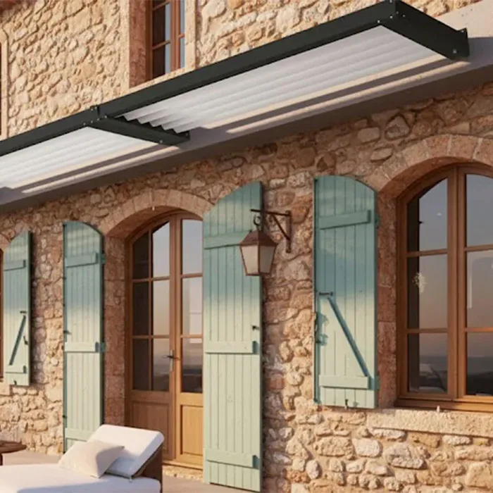 Auvent brise-soleil à structure anthracite et lames claires sur une façade en pierre à volets