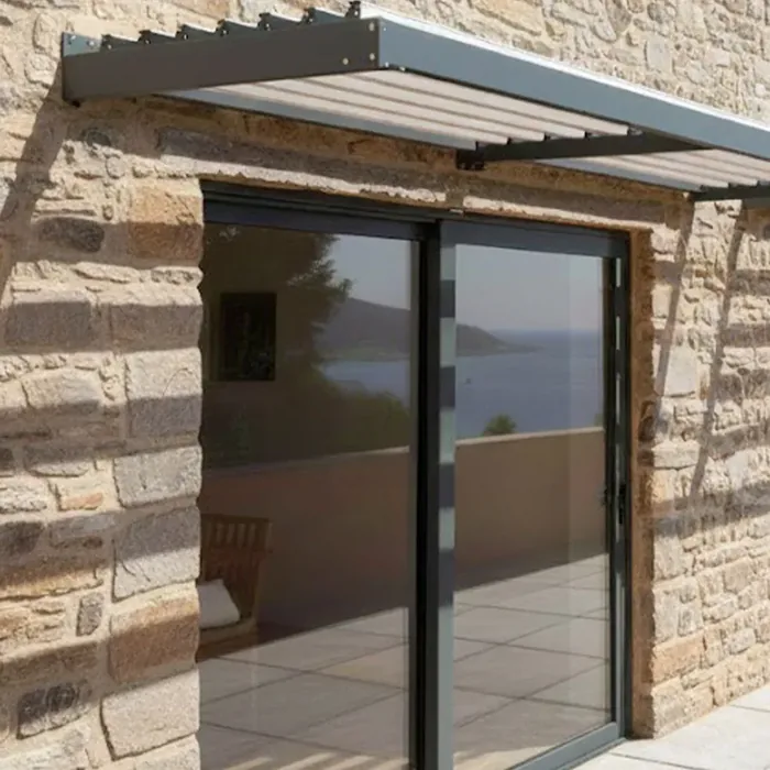Auvent brise-soleil à lames fixes en aluminium au-dessus d'une baie vitrée sur une façade en pierre