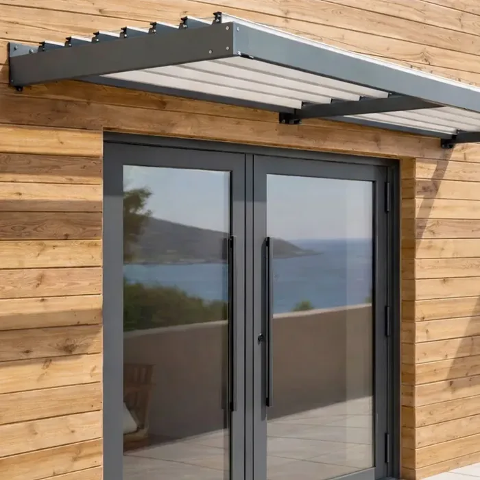 Auvent brise-soleil à lames fixes au-dessus d'une porte d'entrée vitrée à deux battants sur un bardage bois
