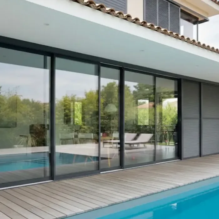Baie coulissante aluminium 4 vantaux anthracite en façade d'une maison contemporaine au bord d'une piscine