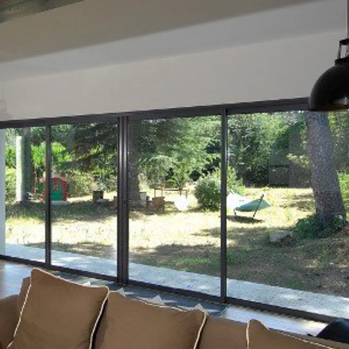 Coulissant à galandage 4 vantaux anthracite dans un séjour, ouvert sur un jardin