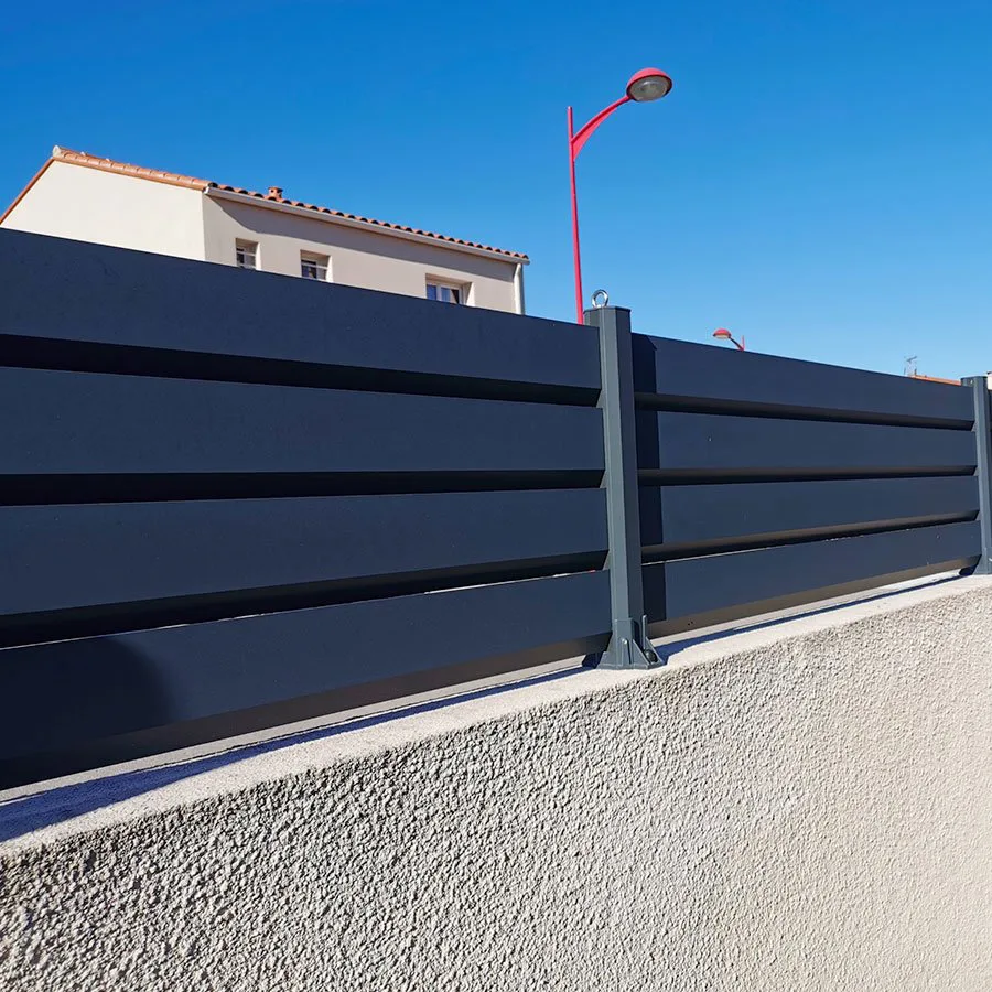 Clôture brise vue aluminium anthracite RAL 7016 sur un muret enduit le long d'une rue