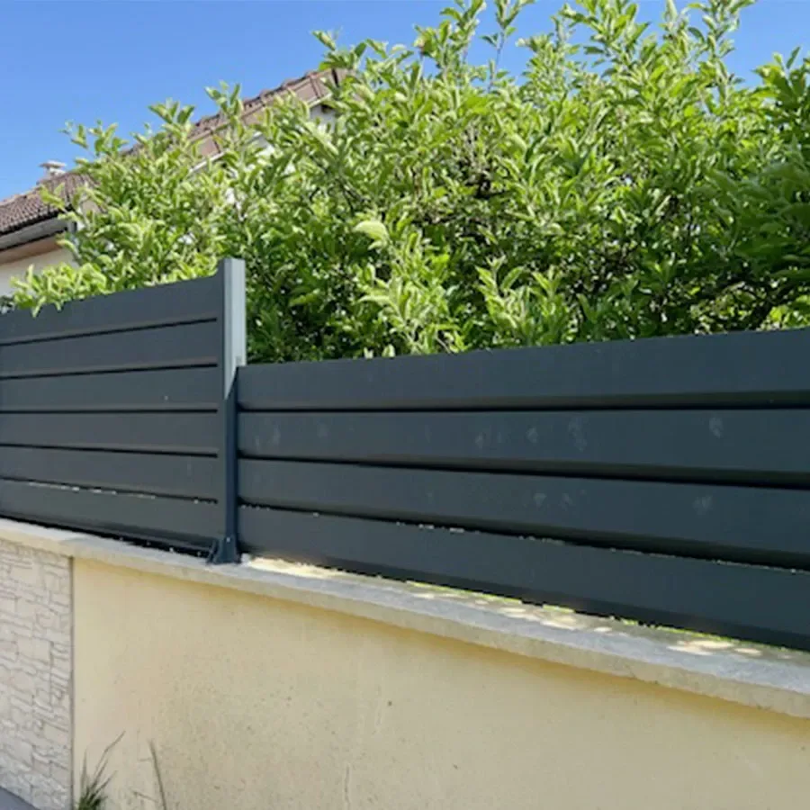 Clôture brise vue aluminium anthracite posée en redans sur un muret qui suit une pente